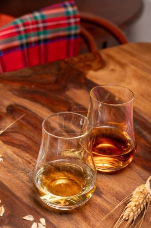 Verkostung verschiedener schottischer Whiskys mit starken alkoholischen Getränken, einem Glas Whisky und farbenfrohem Scotch Tartan im Hintergrund aus nächster Nähe