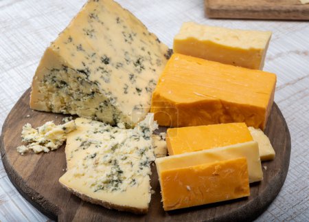 Englische Käsekollektion, reifer und farbiger Cheddar-Käse und halbweicher, krümeliger alter Stilton-Blauschimmelkäse hautnah auf dem Teller
