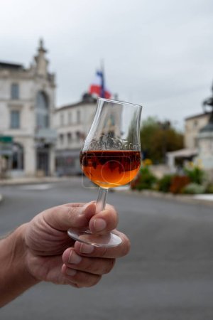 Photo for Tasting of aged in barrels cognac alcohol drink and view on old streets and houses in town Cognac, Grand Champagne, Charente, strong spirits distillation industry, France - Royalty Free Image