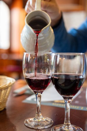 Einschenken von rotem Beaujolais-Wein in Gläser während der Feier des Ernteabschlusses und der ersten Verkaufsfreigabe am dritten Donnerstag im November aus weißem Keramikkrug in Limouges, Frankreich