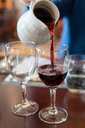 Einschenken von rotem Beaujolais-Wein in Gläser während der Feier des Ernteabschlusses und der ersten Verkaufsfreigabe am dritten Donnerstag im November aus weißem Keramikkrug in Limouges, Frankreich