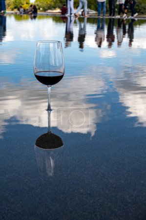 Photo for Tasting of Bordeaux blended red wine with wine city Bordeaux on background, left bank of Gironde Estuary, France. Glass of red French wine served outdoor. - Royalty Free Image