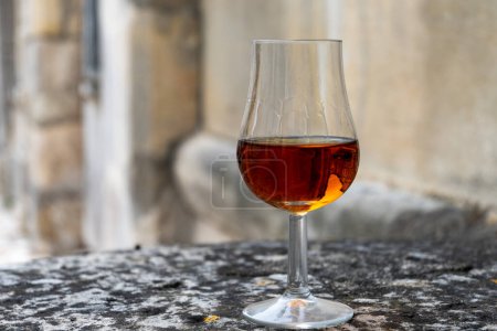 Tasting of aged in barrels cognac alcohol drink and view on old streets and houses in town Cognac, Grand Champagne, Charente, strong spirits distillation industry, France