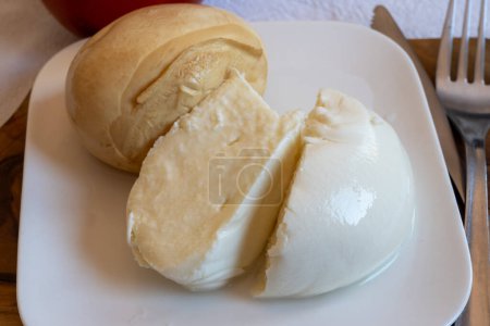 Leckeres italienisches Essen, kleine Bällchen mit geräuchertem und weißem Mozzarella-Weichkäse, serviert auf weißem Brett