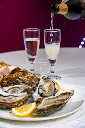 Moluscos frescos de ostras grandes francesas, holandesas, pacíficas o japonesas, tamaño número 1, servidos con vino seco de champán