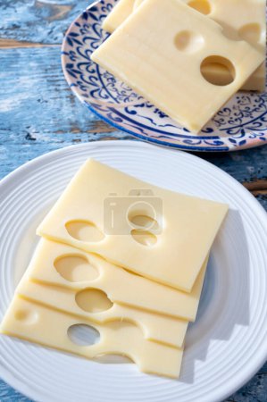 Swiss cheese collection, yellow emmentaler or emmental cheese with round holes sliced close up