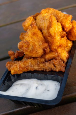 Seafood, outdoor eating of diep-fried cod fish pieces served with remoulade sauce, Dutch street food
