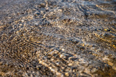 Crystal clear sea water texture with glare from the sun, wallpaper, nature background