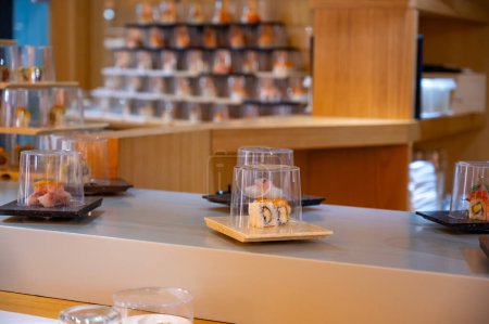 Japanese cuisine, modern restaurant with sushi, sashimi and other Japanese dishes served on moving belt across restaurant, self-service lunch cafe