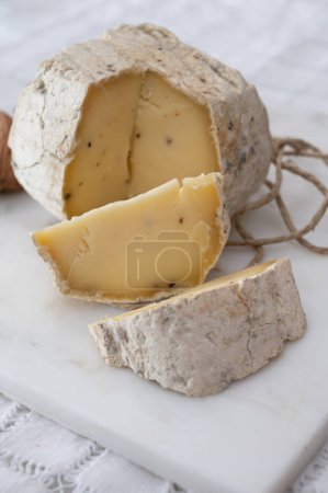 Italian small piece of hard cheese truffelino romano with black summer truffles mushrooms close up