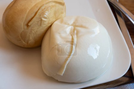 Leckeres italienisches Essen, kleine Bällchen mit geräuchertem und weißem Mozzarella-Weichkäse, serviert auf weißem Brett