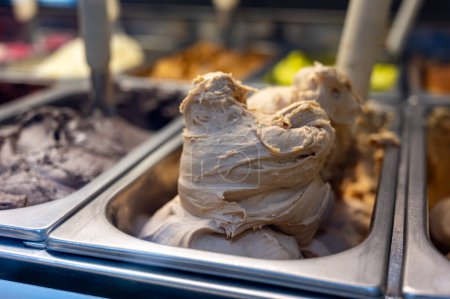 Assortment of fresh made Italian artisanal ice creams in refrigerator close up, dairy walnuts ice cream dessert, Milan, Italy