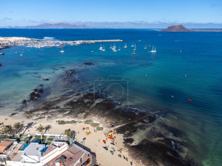 Aerial view Corralejo town, harbour, black rocks, blue water, Lobos and Lanzarote islands, Fuerteventura, Canary islands, Spain, winter sun vacation
