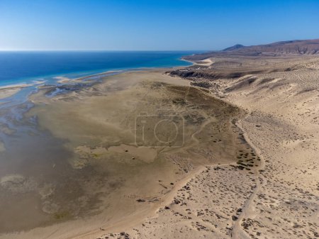 Vista aérea sobre dunas de arena y aguas turquesas azules de la playa de Sotavento, Costa Calma, Fuerteventura, Islas Canarias, España en invierno