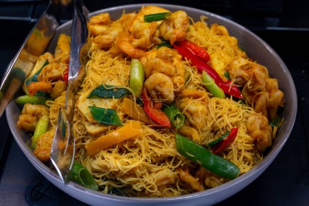 Comida asiática local, plato de fideos singapurenses con verduras, camarones fritos y carne de pollo en un tazón