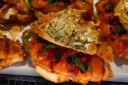 Croissants de mantequilla en exhibición en panadería artesanal en Londres, lleno de salmón salvaje ahumado escocés y caviar, decorado con lámina de oro real de 24 quilates de cerca