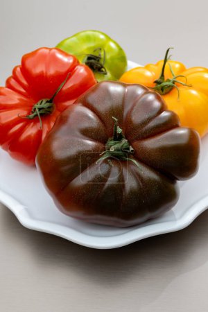 Vielfalt an farbenfrohen leckeren reifen französischen Tomaten vom Bauernmarkt in der Bretagne auf dem Teller, Nahaufnahme auf dem Holztisch