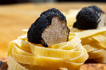 Cooking vegetarian pasta with Italian black summer truffle, tasty aromatic mushroom, close up