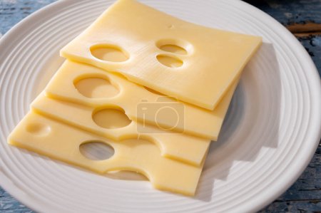Swiss cheese collection, yellow emmentaler or emmental cheese with round holes sliced close up