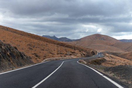 Foto de Camino de asfalto de montaña en coloridas colinas basales remotas y montañas del Macizo de Betancuria, Fuerteventura, Islas Canarias, España, destino de viaje - Imagen libre de derechos