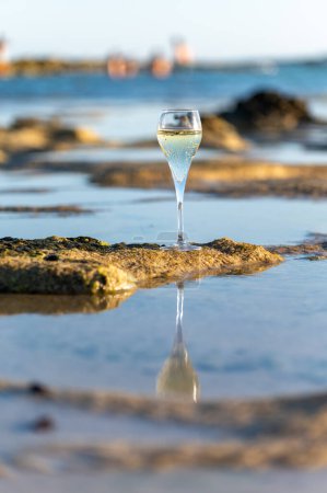 Glass of cava or champagne sparkling wine, winter vacation, low tide on Dunes Corralejo sandy beach, Fuerteventura, Canary islands, Spain