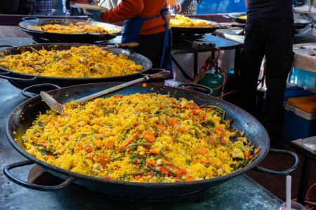 Comida callejera en Londres, patio de comidas en el mercado de Portobello Road Saturday, paella colorida fresca preparada con arroz y mariscos en una sartén grande, lista para comer