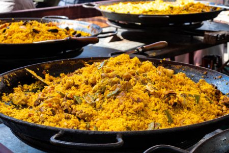 Street food in London, food court on Portobello road Saturday market, fresh prepared colorful paella with rice and sea food in big pan, ready to eat