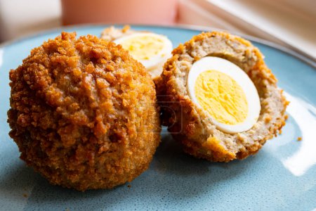 Traditional street food in UK, stuffed fried hot Scotch eggs with breadcrumbs close up