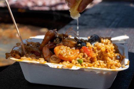 Comida callejera en Londres, patio de comidas en Portobello Road mercado del sábado, paella colorida fresca preparada con arroz y mariscos en caja con limón, listo para comer
