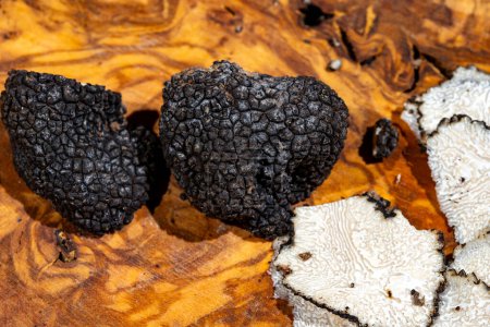 Cooking with Italian black summer truffle, tasty aromatic mushroom on wooden board