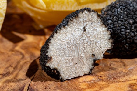 Cooking with Italian black summer truffle, tasty aromatic mushroom on wooden board