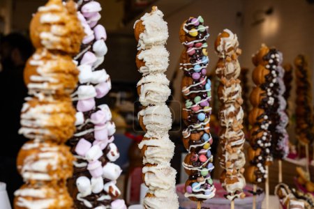 Süßwarenladen in London, verschiedene süße Profiteroles mit Dekoration auf Spießen bereit zum Essen