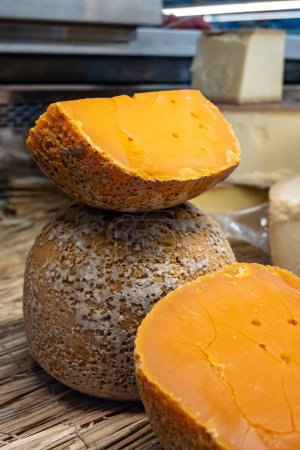 Pieces of native French aged cheese Mimolette, produced in Lille with greyish curst made by special cheese mites close up on market