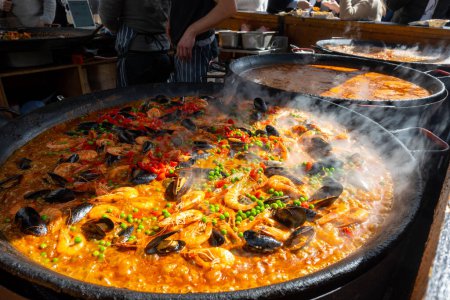Street Food in London, Food Court an der Portobello Road samstags Markt, frisch zubereitete bunte Paella mit Reis und Meeresfrüchten in großer Pfanne, fertig zum Essen