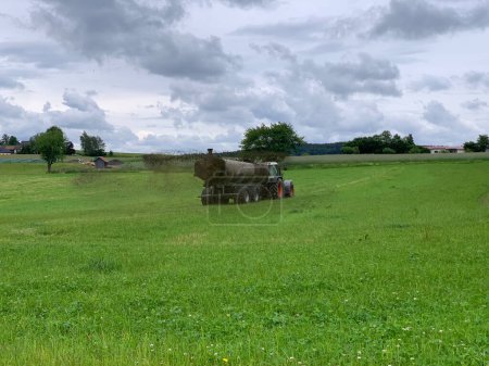 Un tractor de granja rocía su estiércol del petrolero sobre un campo. El estiércol se utiliza como fertilizante en la agricultura.