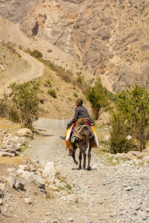 Foto de Haft Kul, Tayikistán, 21 de agosto de 2023: Pequeño niño montando un burro en las montañas Fann - Imagen libre de derechos