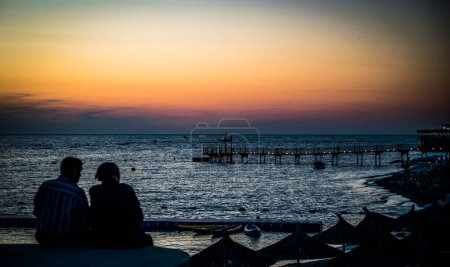 Téléchargez les photos : Couple amoureux regardant coucher de soleil ensemble. silhouette de derrière assis profiter de la vue coucher de soleil mer en vacances. - en image libre de droit