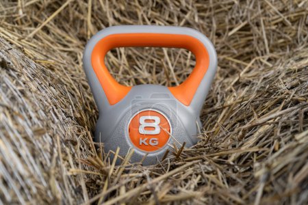 Photo for Heavy kettlebell on the hay. Healthy fitness lifestyle autumn fall composition for Halloween or Thanksgiving. Gym workout and sport training concept on a farm. - Royalty Free Image