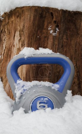 Téléchargez les photos : Kettlebell poids dans une neige. Équipement lourd entraînement de gymnastique à domicile d'hiver. Kettlebells de fitness d'entraînement de force, cloche de bouilloire d'exercice avec poignée de poignée. Style de vie sain, espace de copie sur fond en bois. - en image libre de droit