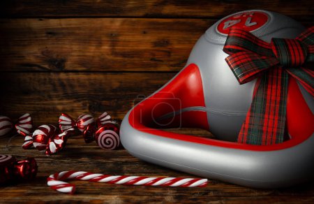 Photo for Heavy kettlebell with gift wrap bow. Exercise equipment as a Christmas present idea. Healthy fitness lifestyle holiday season concept, composition on wooden background, with candy decor pendants. - Royalty Free Image