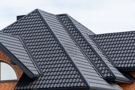 Foto de Techo de perfil de metal negro instalado en una casa moderna. Tipos modernos de materiales para techos. Construcción moderna. - Imagen libre de derechos