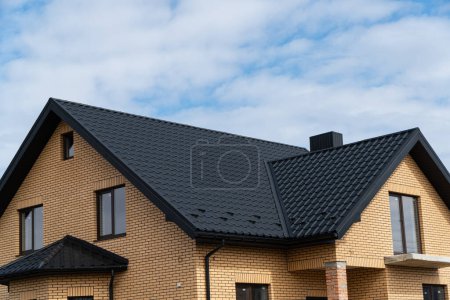 Photo for New brick house. The modern house with plastic windows and a black roof of corrugated sheet. Metal roofing. - Royalty Free Image