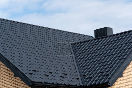 Ein Fragment des Daches aus metallenen Dachziegeln. Modernes Metalldach. Dachkonstruktion des Hauses.