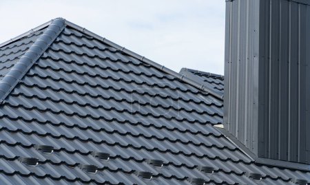 A fragment of the roof made of metal roof tiles. Modern roof made of metal.