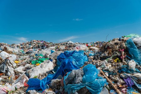 Foto de Una pila de basura en un vertedero contra un cielo azul. Desechos de plástico en vertederos. Concepto de ecología. - Imagen libre de derechos