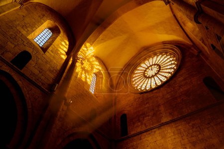 Téléchargez les photos : Intérieur d'une très ancienne abbaye italienne avec sa grande rosace d'où des filtres lumineux réfléchissent les voûtes en pierre de l'église - en image libre de droit