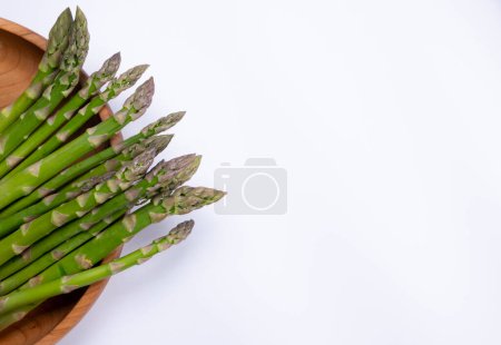 green fresh asparagus on wooden plate,on white background with place to insert text,copy space healthy food concept. High quality photo