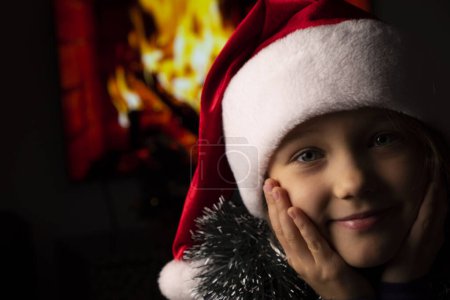 Close-up of girls in Santas hat on background of fireplace. High quality photo