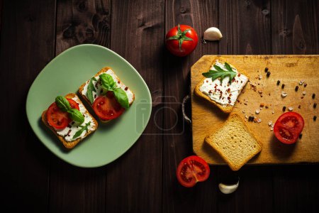 Photo for Delicious sandwiches of cream cheese with tomatos salt and pepe on a dark wooden background - Royalty Free Image