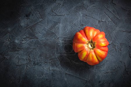 Foto de Rojo acanalado tomate cuore di bue en un fondo oscuro vista superior - Imagen libre de derechos